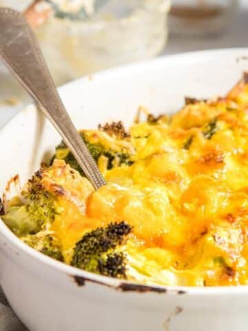 close up of cheesy broccoli in white casserole dish