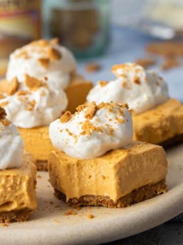 bite out of a pumpkin cheesecake bars on plate with more bars