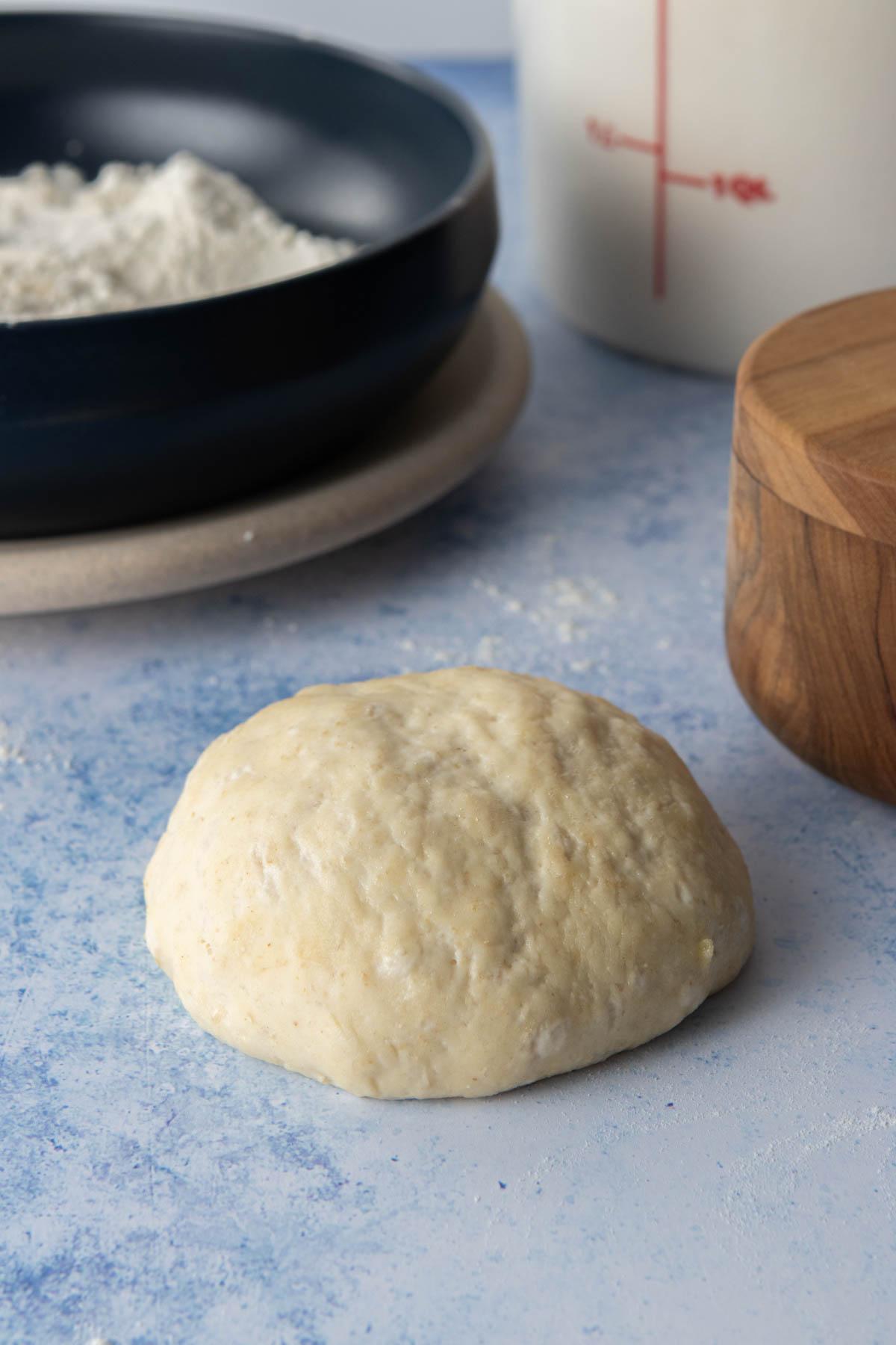 single serving pizza dough ball with ingredients behind it