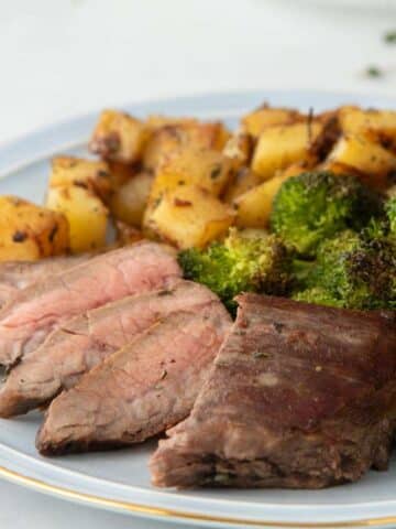 close up of sliced Flank Steak with sides behind
